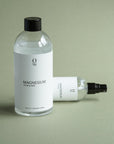 Foto van een voordelige 500ml navulfles magnesiumolie met daarnaast een liggend 100ml magnesium olie flesje. Ideaal om de magnesium spray eenvoudig bij te vullen en dagelijks te gebruiken. Beide producten zijn gemakkelijk te bestellen in onze webshop.
