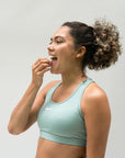 Foto van een vrouw die na het sporten een magnesiumcapsule inneemt om spierherstel en ontspanning te ondersteunen. Ondersteunt de dagelijkse magnesiumbalans, vermindert vermoeidheid en bevordert welzijn en gezondheid.