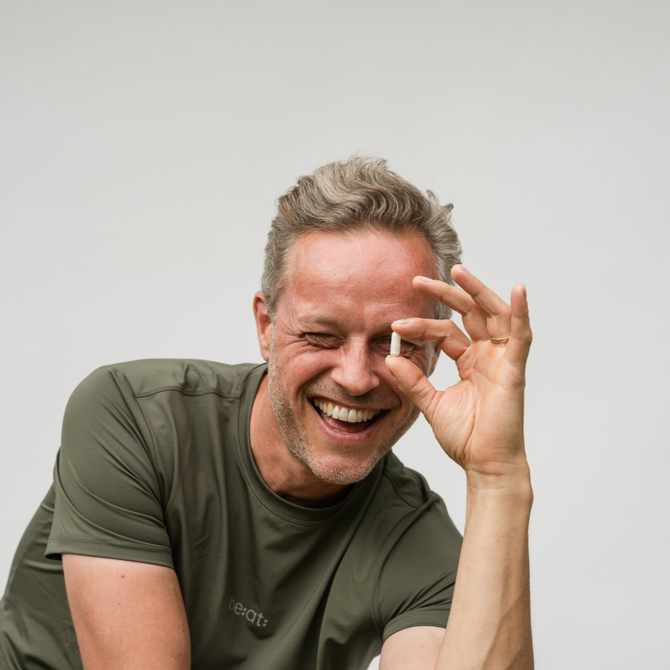 Man met Magnesium glicinaat capsule tussen vingers met glimlach
