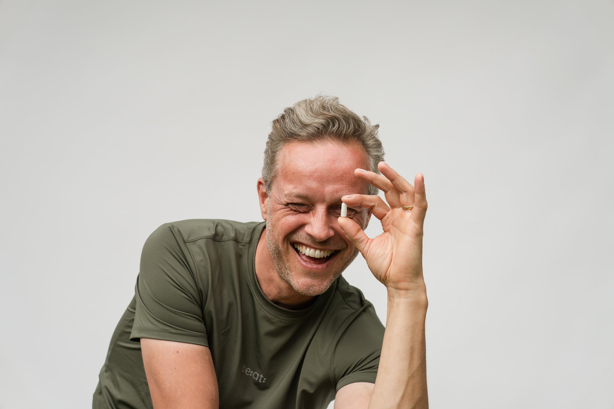 Man met Magnesium glicinaat capsule tussen vingers met glimlach
