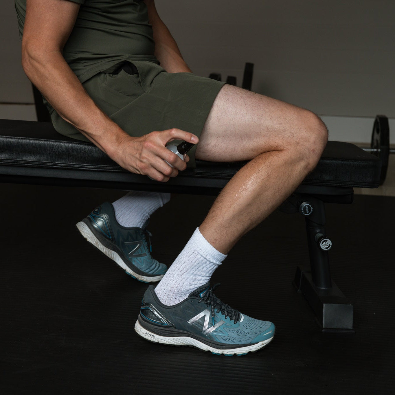 Een mag sprayt magnesiumolie op zijn kuit tegen spierpijn en kramp