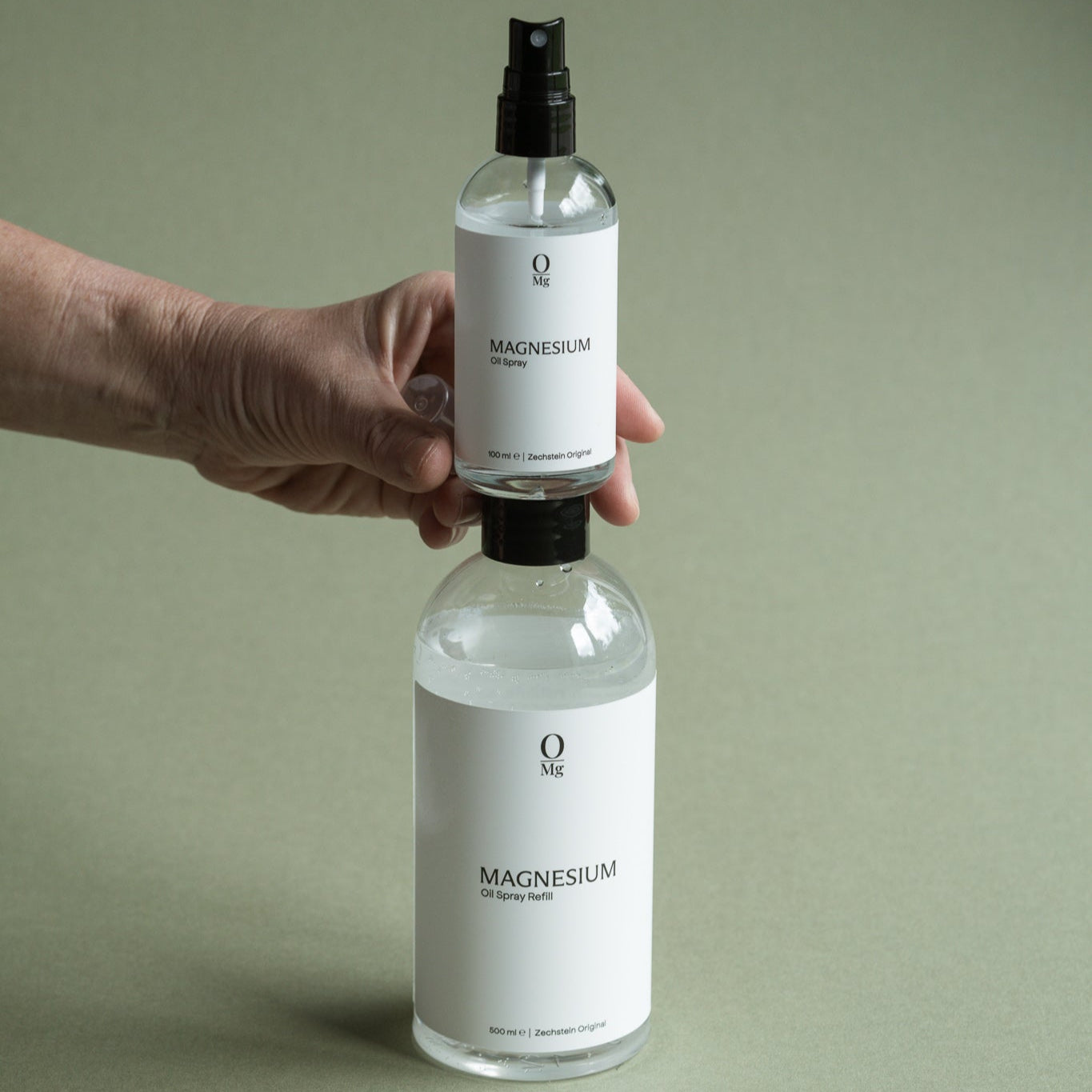 Foto van een voordelige 500ml navul fles magnesiumolie waarop een 100ml magnesiumolie sprayflesje wordt geplaatst. Praktische mgnesium olie set voor dagelijks gebruik en eenvoudig navullen, direct verkrijgbaar in onze webshop.