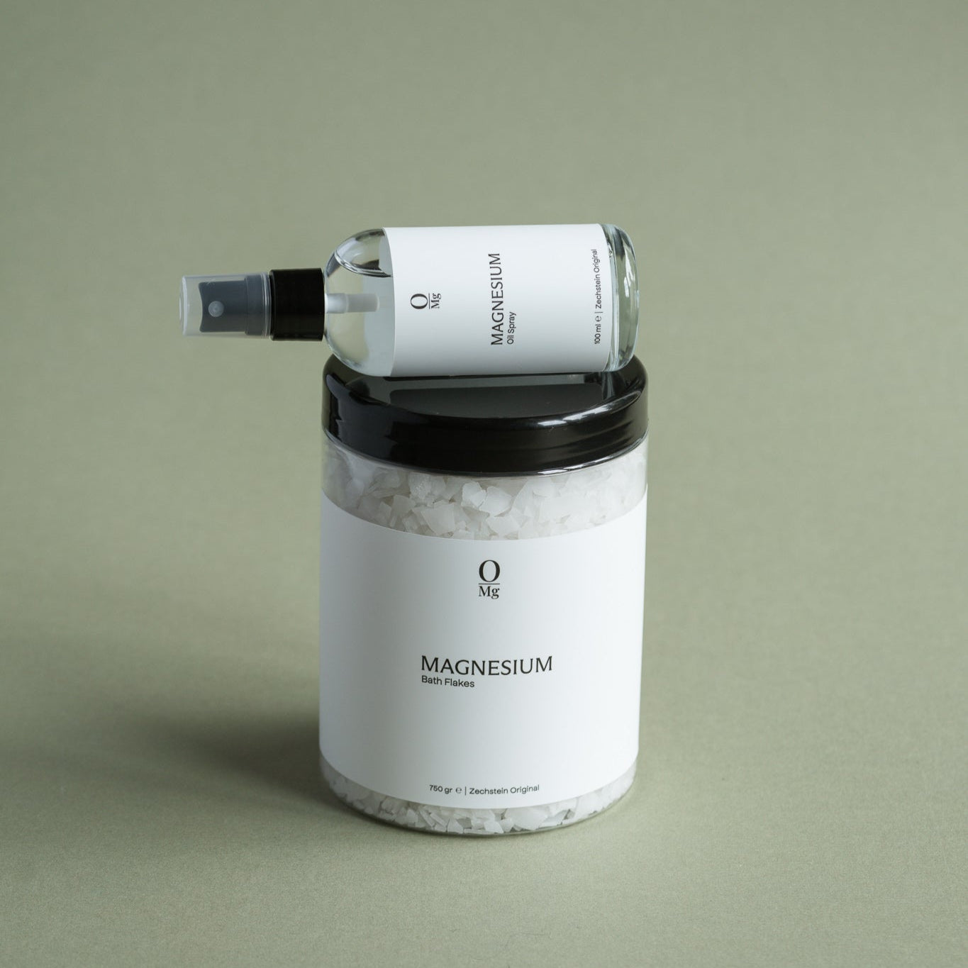 Foto van een pot met oplosbare magnesiumvlokken met daarop een flesje magnesiumolie dat zacht verlicht wordt. Op onze website kun je eenvoudig dit magnesiumassortiment kopen, inclusief olie, vlokken en capsules, voor dagelijkse suppletie en welzijn.