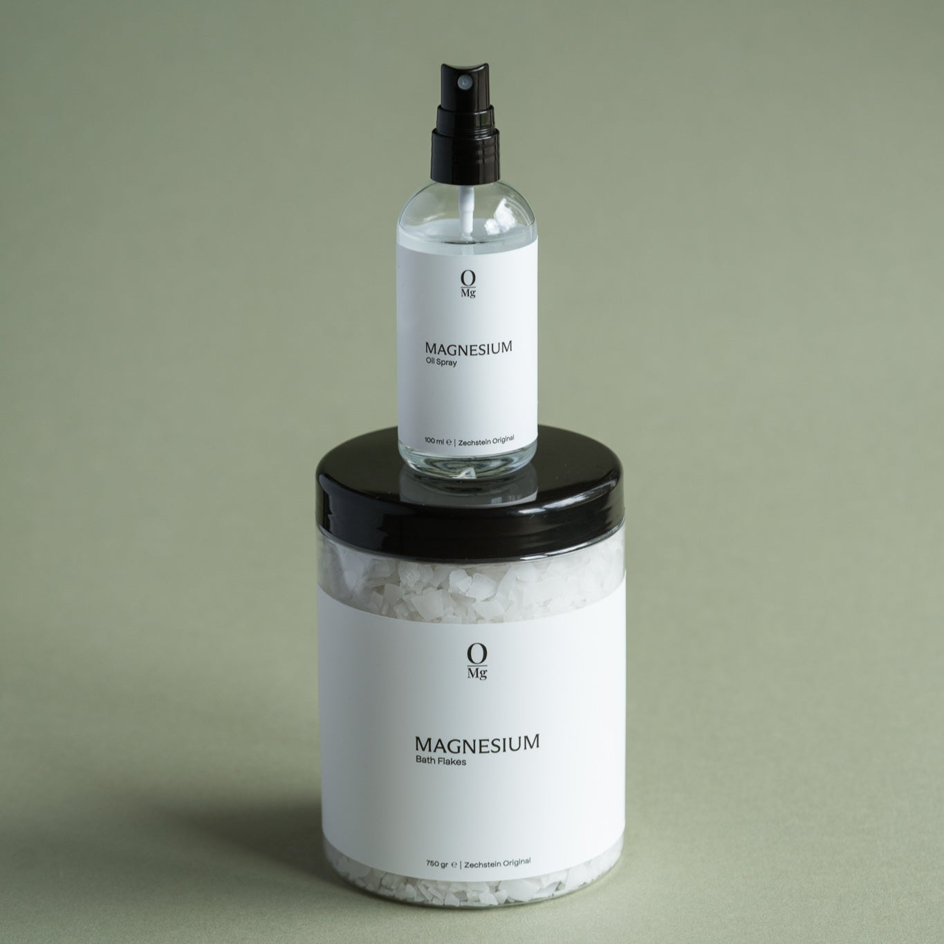 Foto van een pot met oplosbare magnesiumvlokken, waarop een flesje met magnesiumolie staat geplaatst. Perfect voor gebruik in ontspannende baden of voor directe huidtoepassing.