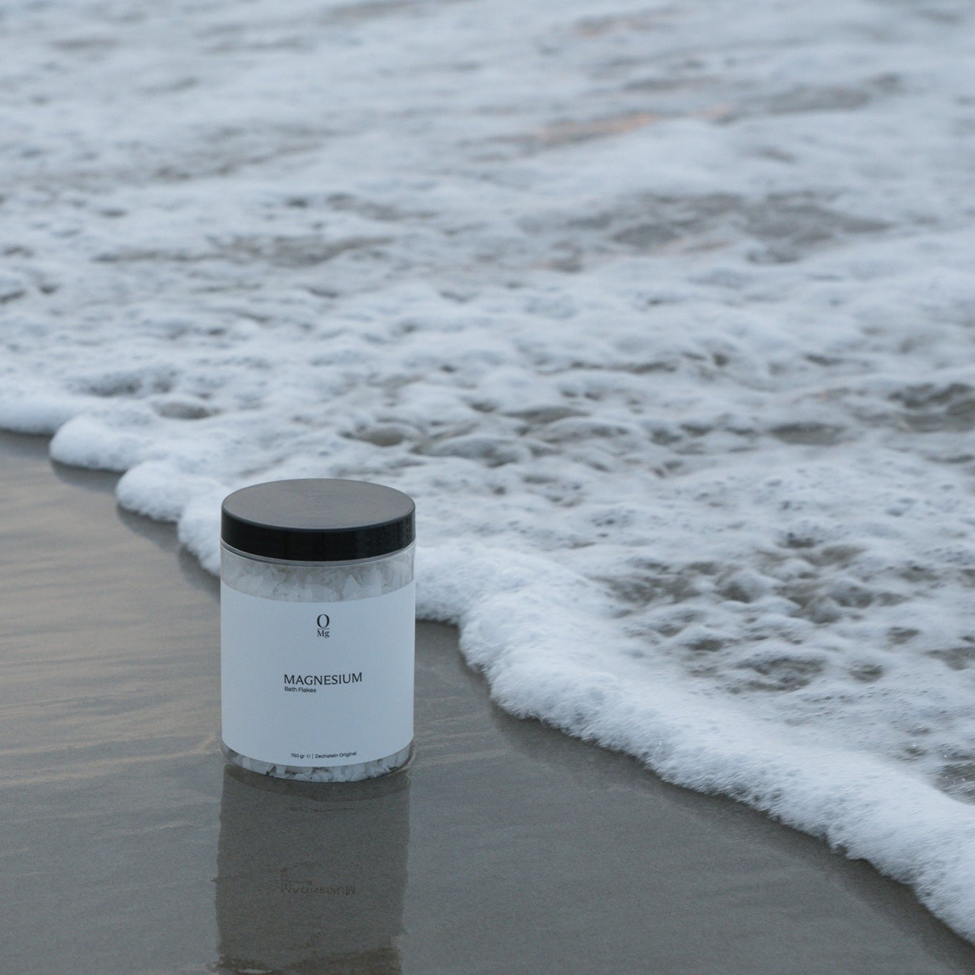 Foto van onze magnesiumpot geplaatst in de branding op het strand. Ondersteunt diepe slaap, ontspanning van spieren, gezonde stressniveaus, stabiele bloedsuikers, hart- en botgezondheid en kan helpen bij PMS en hormonale balans. Gemakkelijk te bestellen via onze webshop.