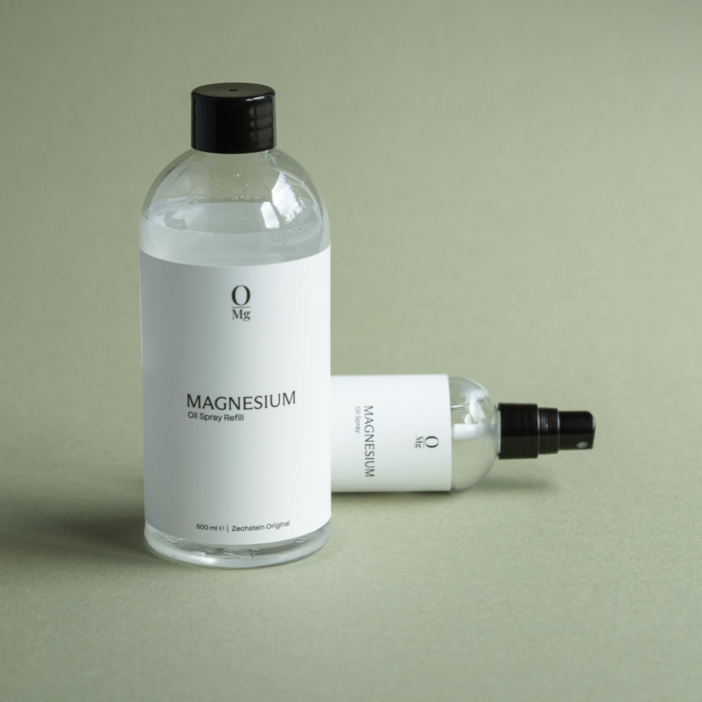 Foto van een voordelige 500ml navulfles magnesiumolie met daarnaast een liggend 100ml magnesium olie flesje. Ideaal om de magnesium spray eenvoudig bij te vullen en dagelijks te gebruiken. Beide producten zijn gemakkelijk te bestellen in onze webshop.