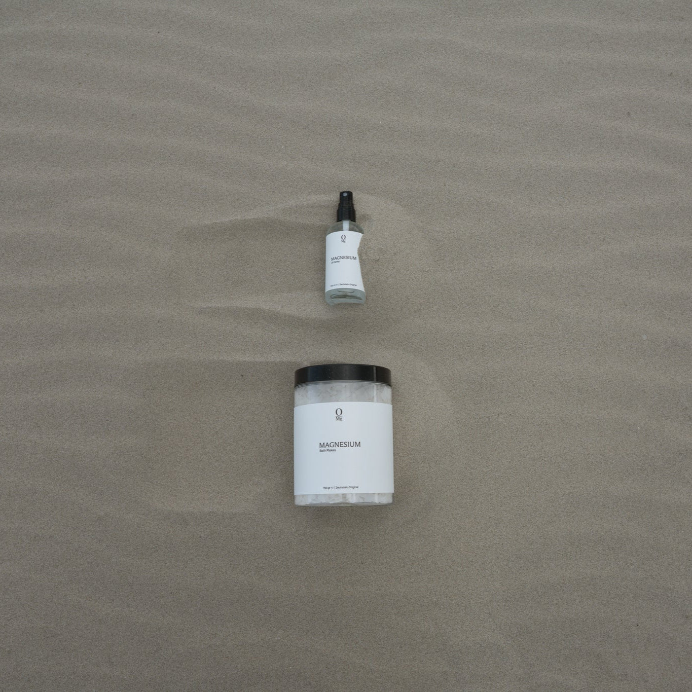 Foto met onderaan een pot met oplosbare magnesiumvlokken en erboven een glazen flesje met magnesiumolie. Ideaal voor ontspanning, spierherstel en dagelijkse magnesiumsuppletie ter ondersteuning van welzijn en een gezonde magnesiumbalans.