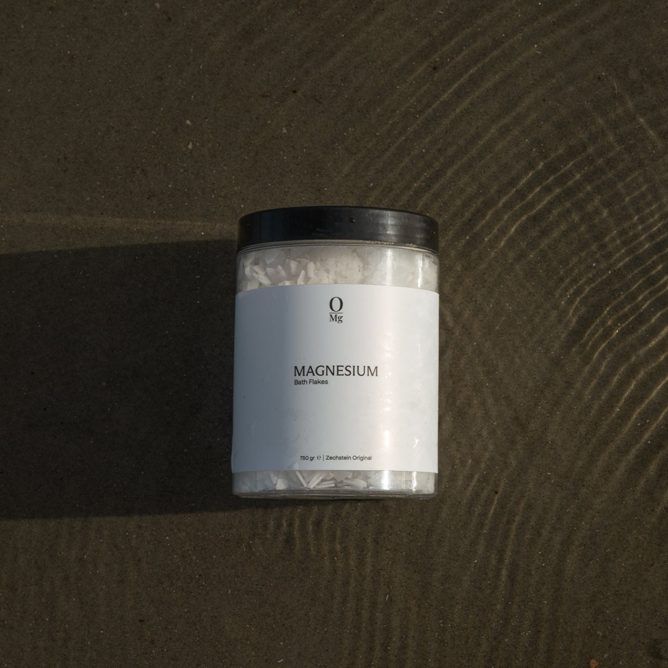 Onze magnesium pot in de branding op het strand, omgeven door zand en water. Ondersteunt ontspanning, spierherstel, diepe slaap en een gezonde magnesiumbalans. Gemakkelijk te koop via onze webshop.