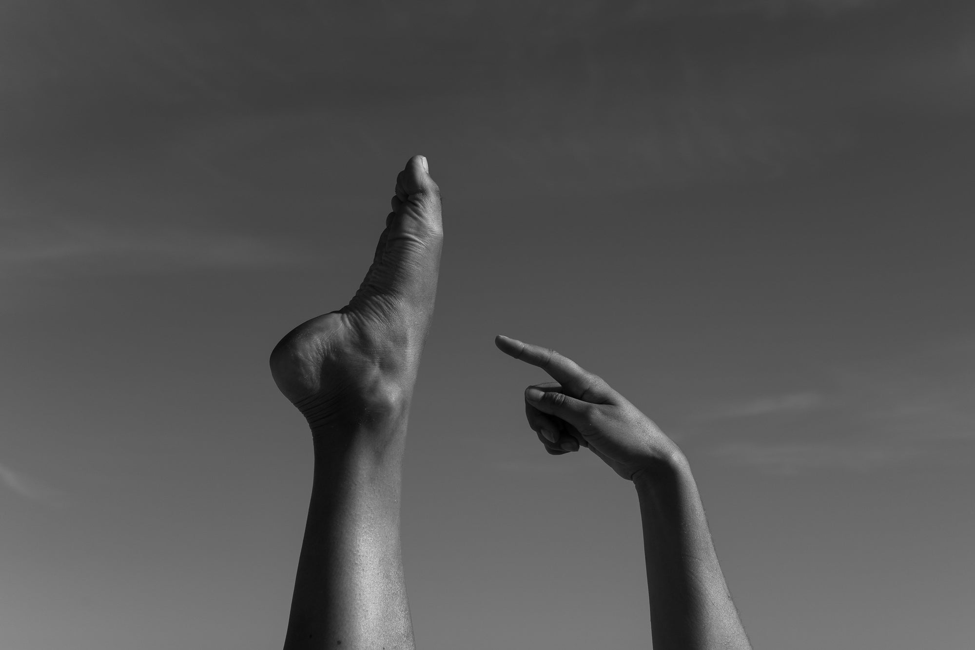 Foto van een voet omhooggestoken terwijl een vinger ernaar wijst, illustrerend voor voetverzorging, ontspanning of massage. magnesium capsules Ideaal voor wellness, selfcare en spierontspanning.