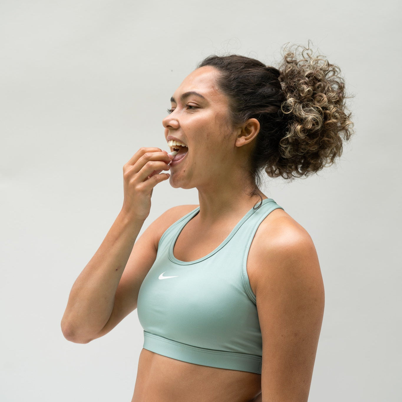 Foto van een vrouw die na het sporten een magnesiumcapsule inneemt om spierherstel en ontspanning te ondersteunen. Ondersteunt de dagelijkse magnesiumbalans, vermindert vermoeidheid en bevordert welzijn en gezondheid.
